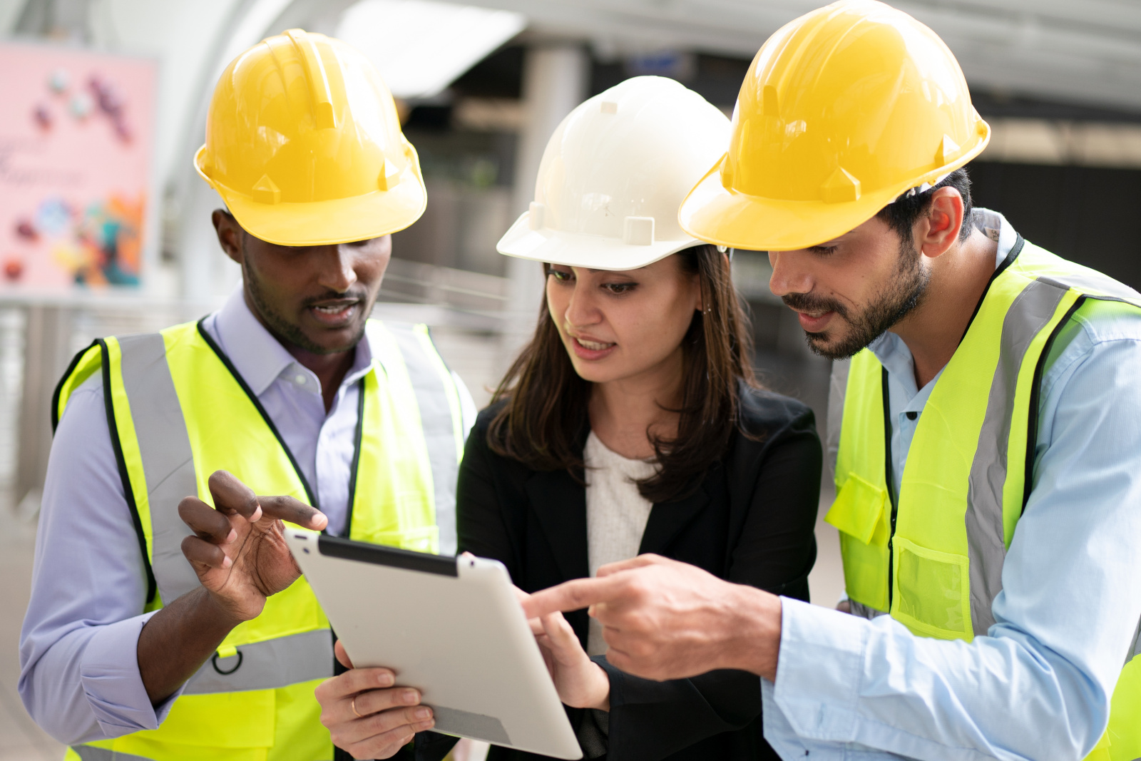Three engineers in safety gear, with tablet, discussing project completion form using NestForms offline surveys