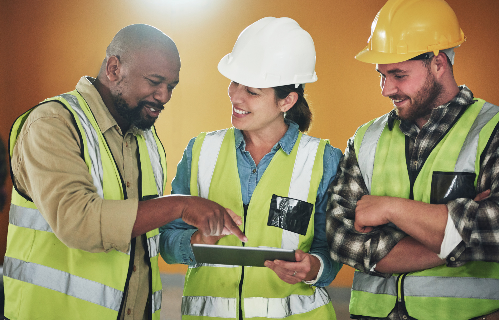 Happy construction project managers in safety gear, signing off a Project completion form using NestForms offline surveys