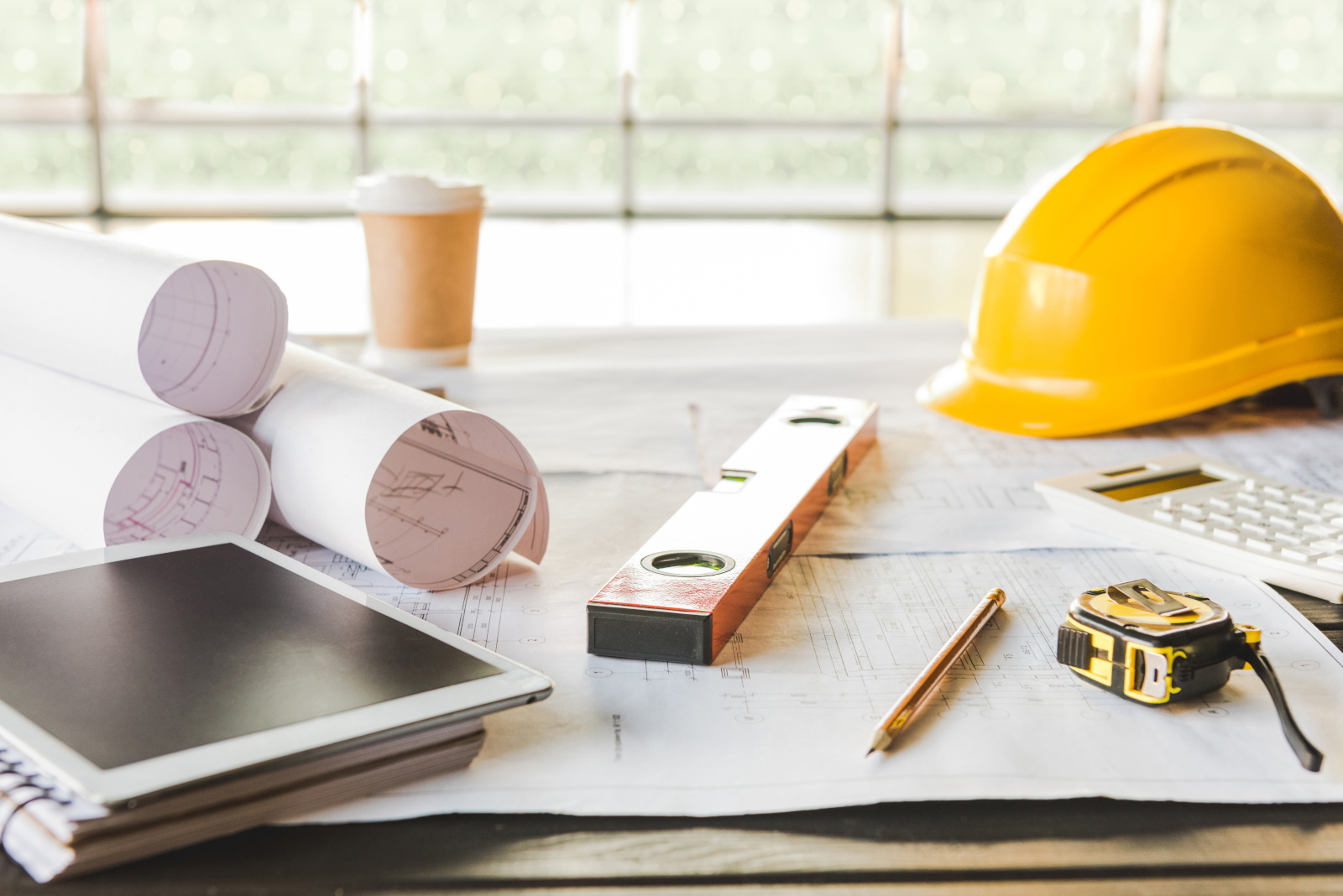 A selection of tools and paper plans including a tablet on a table, onsite: The NestForms GPS Survey App for site handover forms