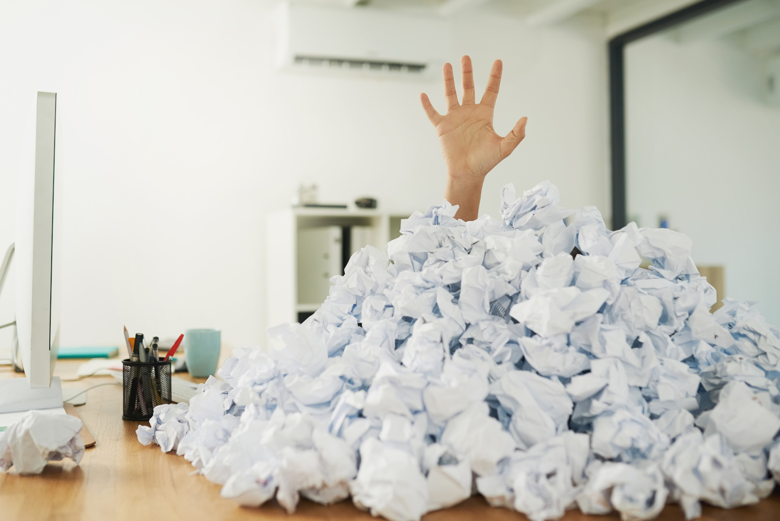 Humorous image of a hand rising behind a mountain of crumpled paper: The NestForms field service management system