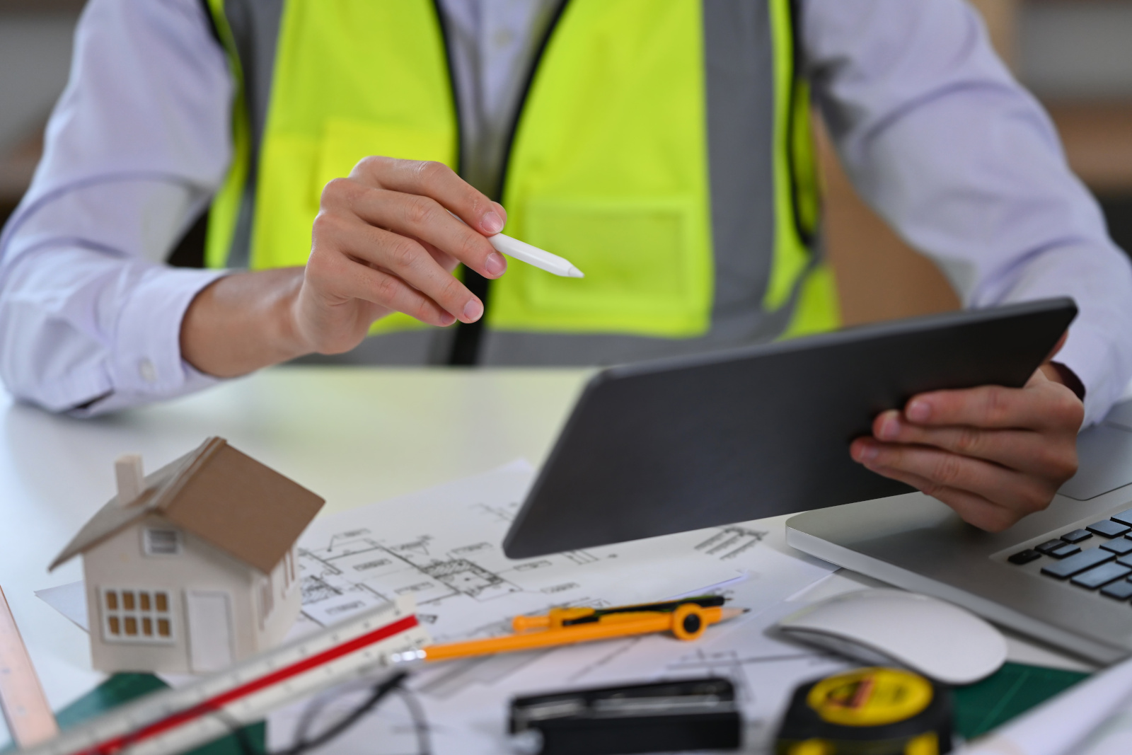 Construction manager at desk with paper plans and tablet filling out a project completion form: NestForms form builder app