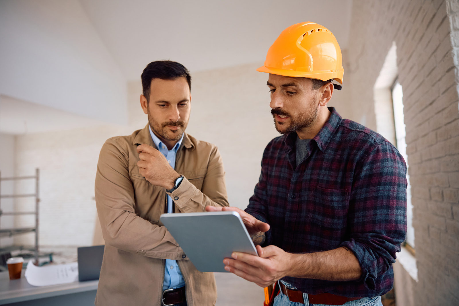 Construction worker holding tablet discussing Punchlist form issues with client before sign off: The NestForms Snag List App