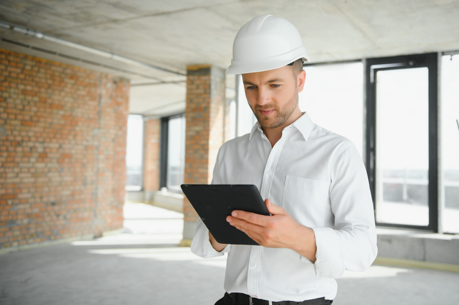 Business architect in hard hat  carrying out work completion report on smart device: NestForms offline surveys