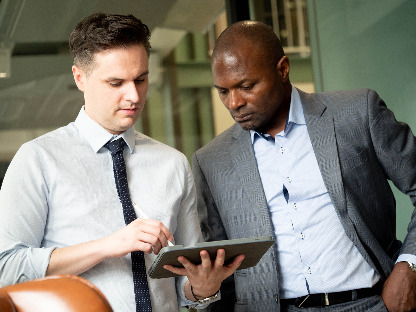 Two project managers onsite having a discussion while looking at a tablet: The NestForms Field Service Software