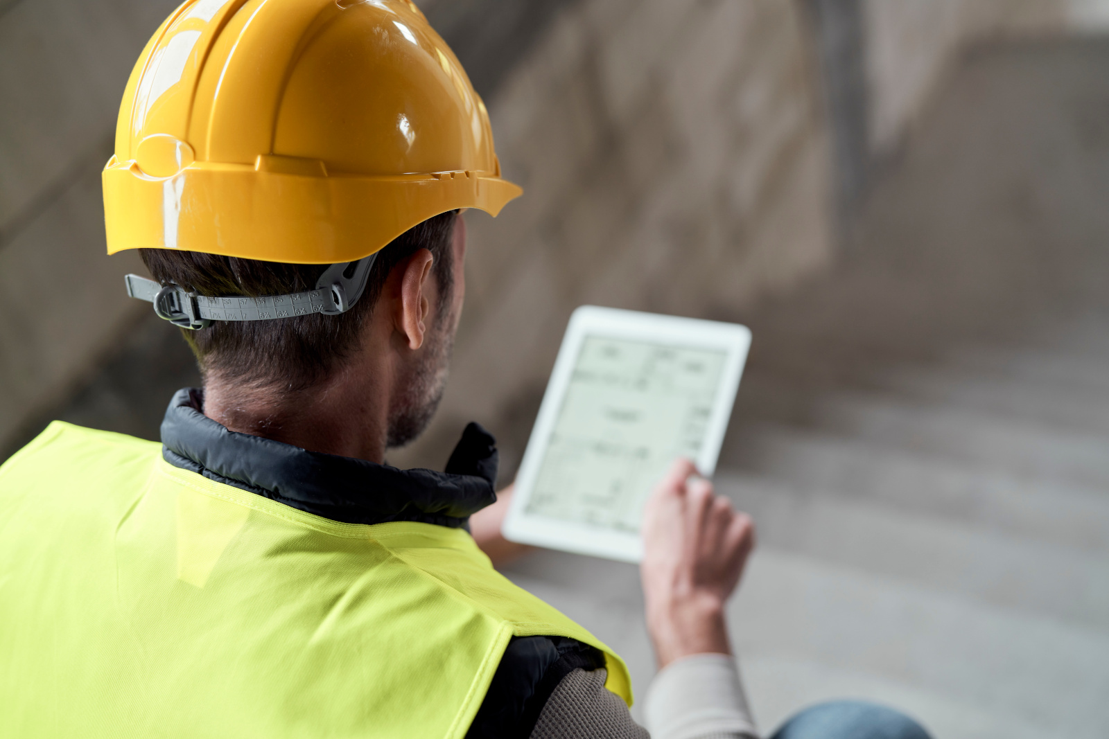 Builder in safety gear with smart device working on a New Build Snagging List Survey: NestForms Mobile Form App