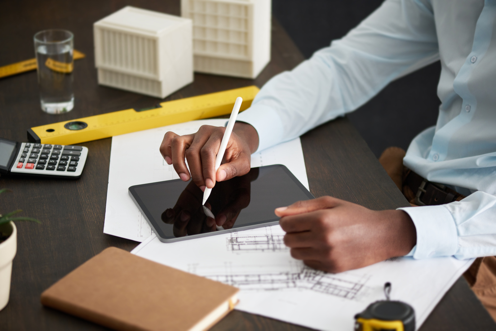 Project Manager at desk with smart device, spirit level and drawings: Data Collection with the NestForms Form Builder App