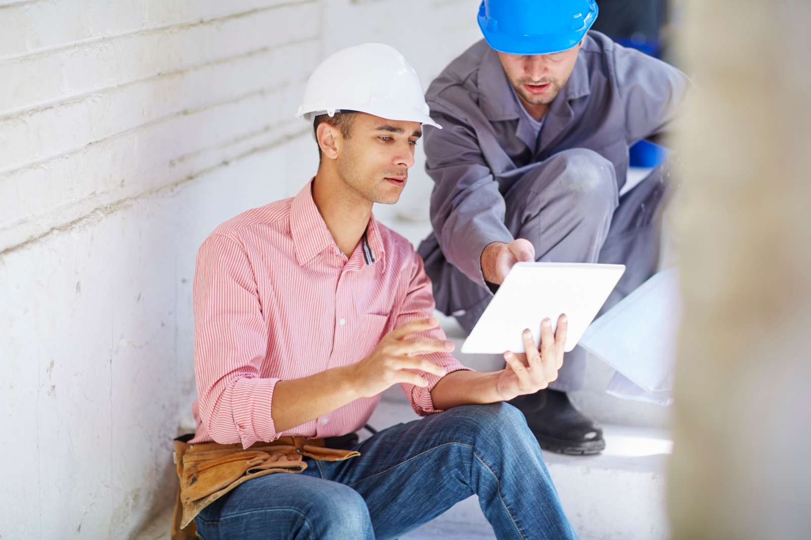 Construction worker and foreman in safety helmets sharing tablet: Punch list form construction, the NestForms surveying app