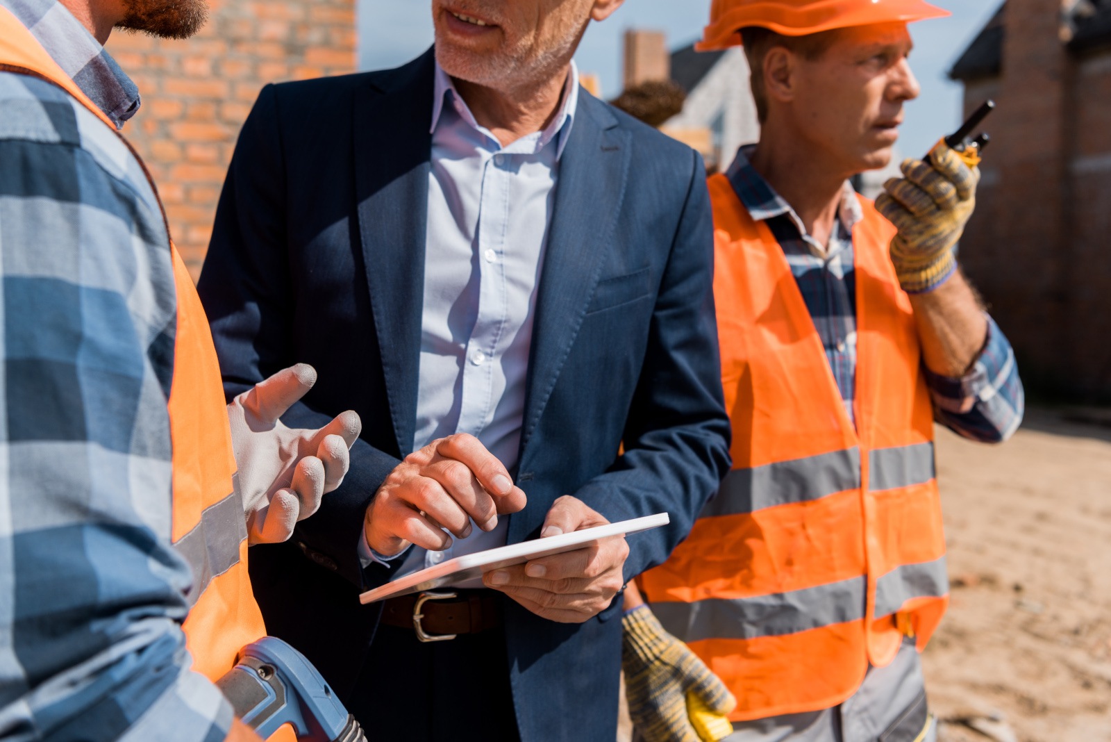 Three construction workers in safety gear onsite working from tablet: NestForms New Build Snagging Checklists
