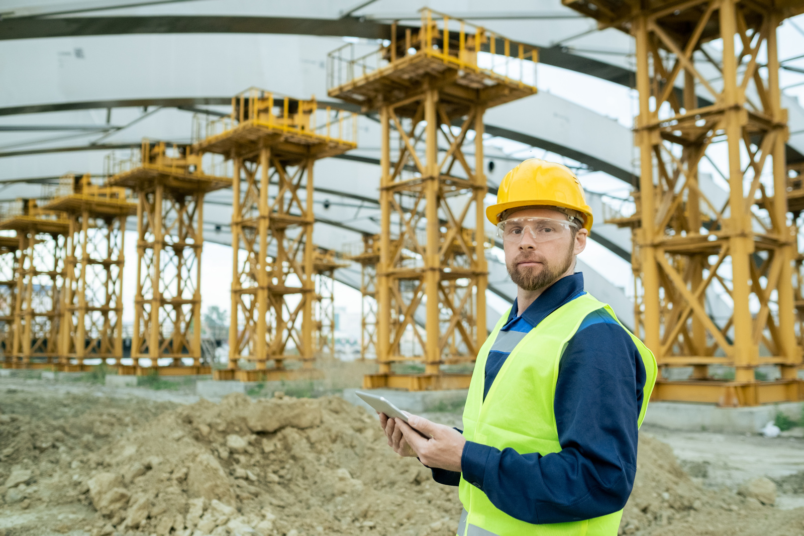 Engineer in safety gear holding tablet using the NestForms GPS Survey App: The NestForms field service management software 