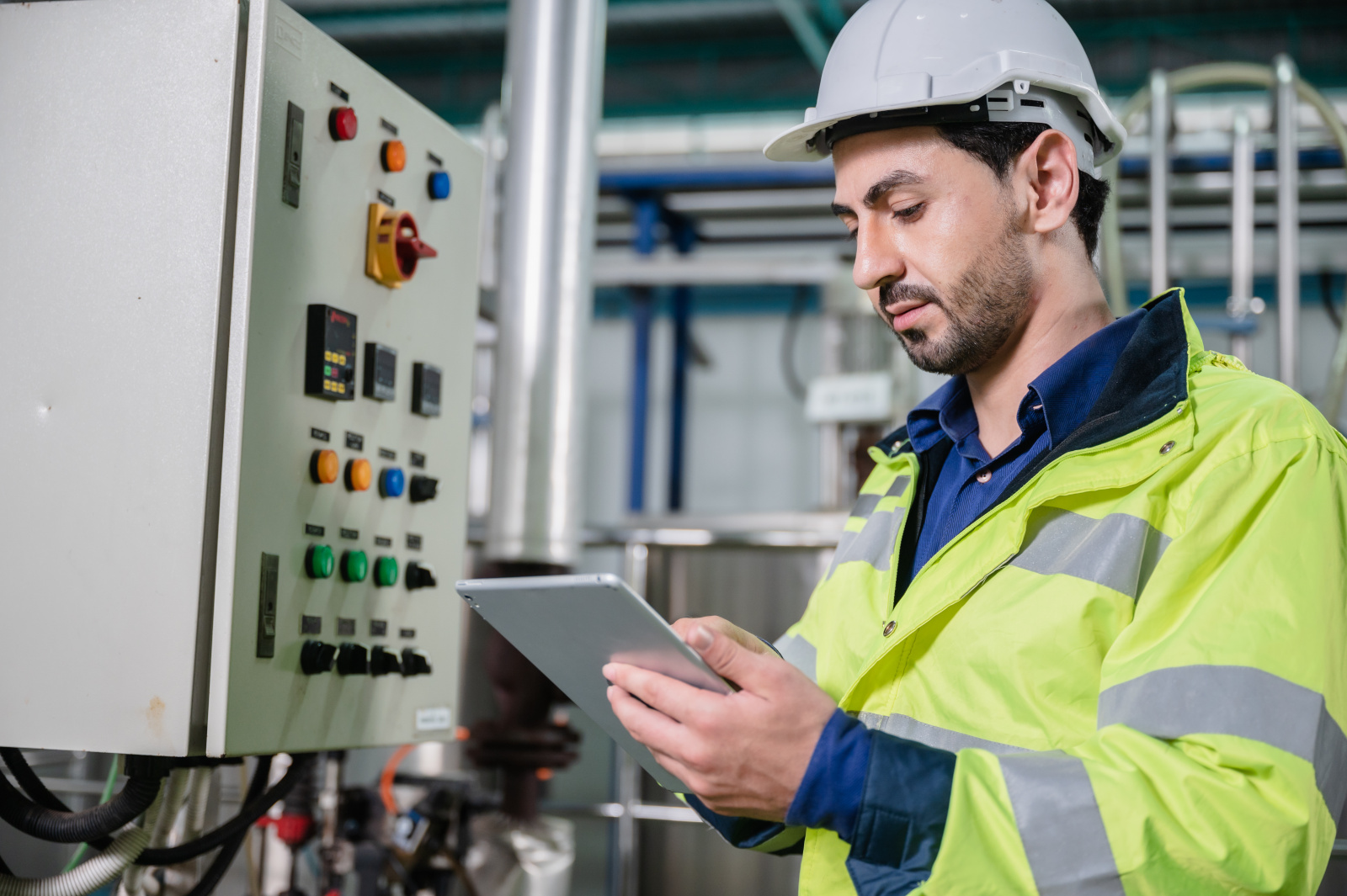 Installation technician inspecting equipment with tablet in factory: The NestForms field service software