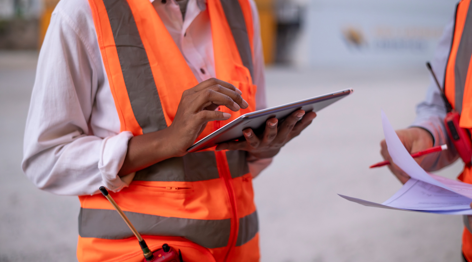 Construction workers onsite in hi-vis vests, one with tablet working on Snag List Form: NestForms Final Inspection Checklist