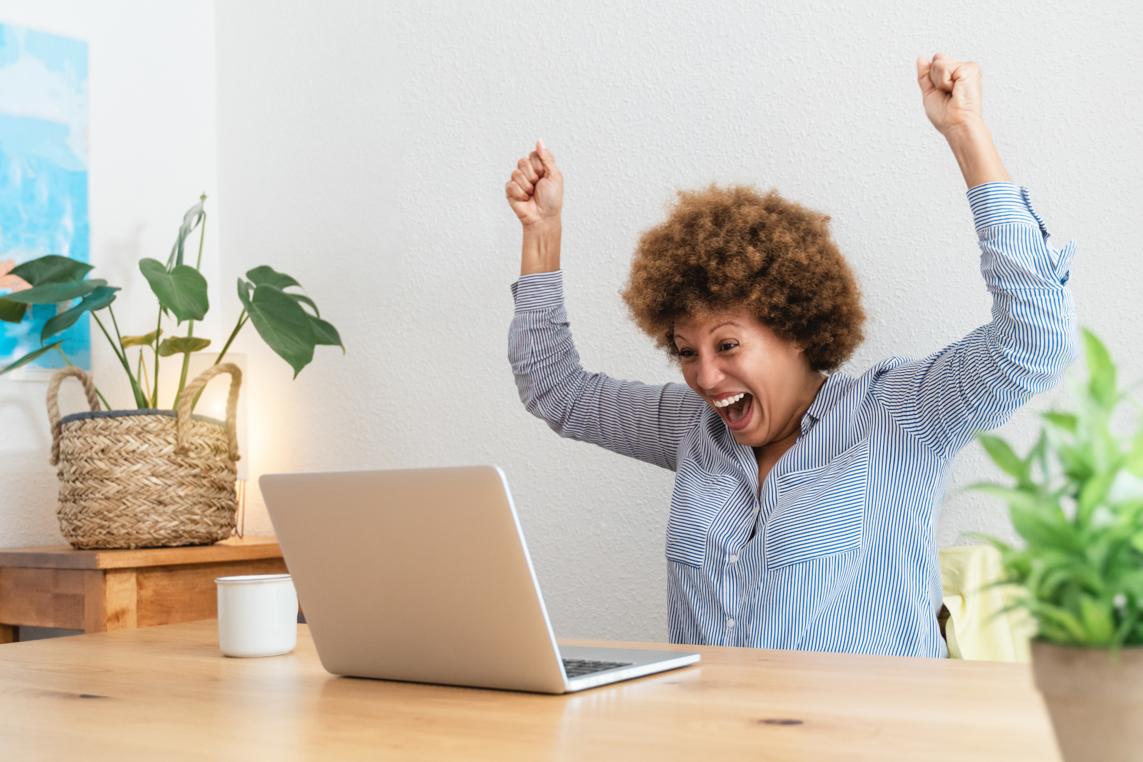 Happy hispanic senior woman celebrate with winning gesture using laptop computer at home office 