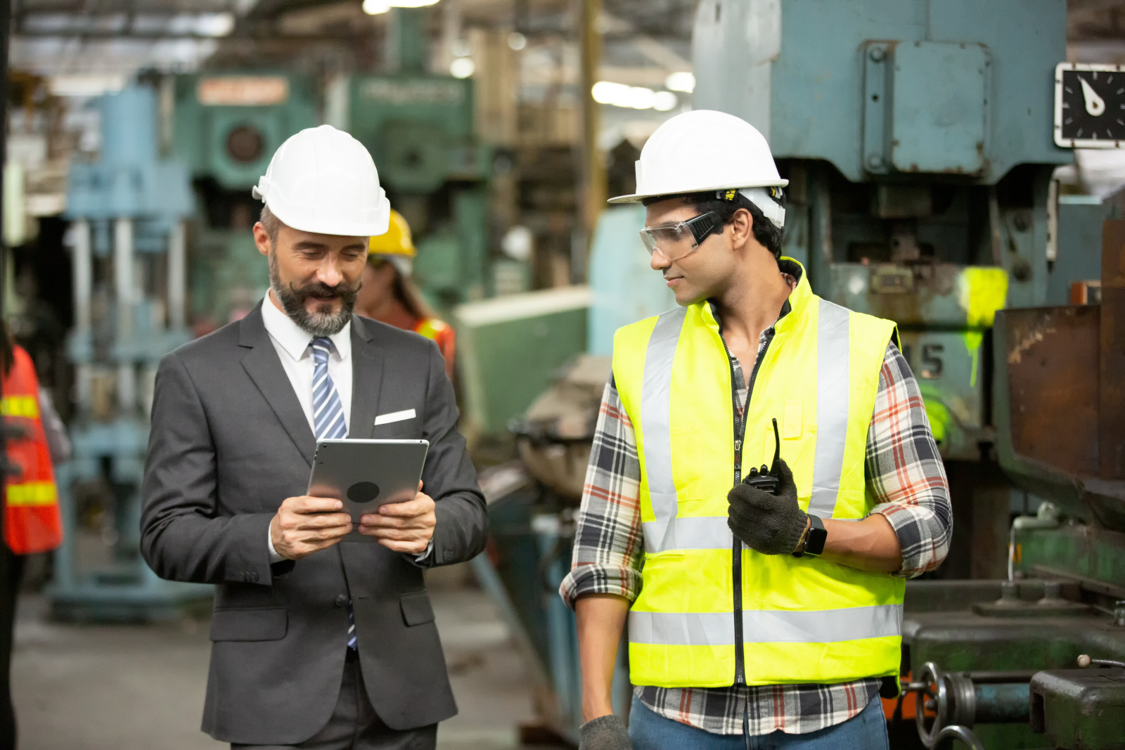 Manager and factory worker in safety gear on factory floor with tablet: The NestForms field service management software