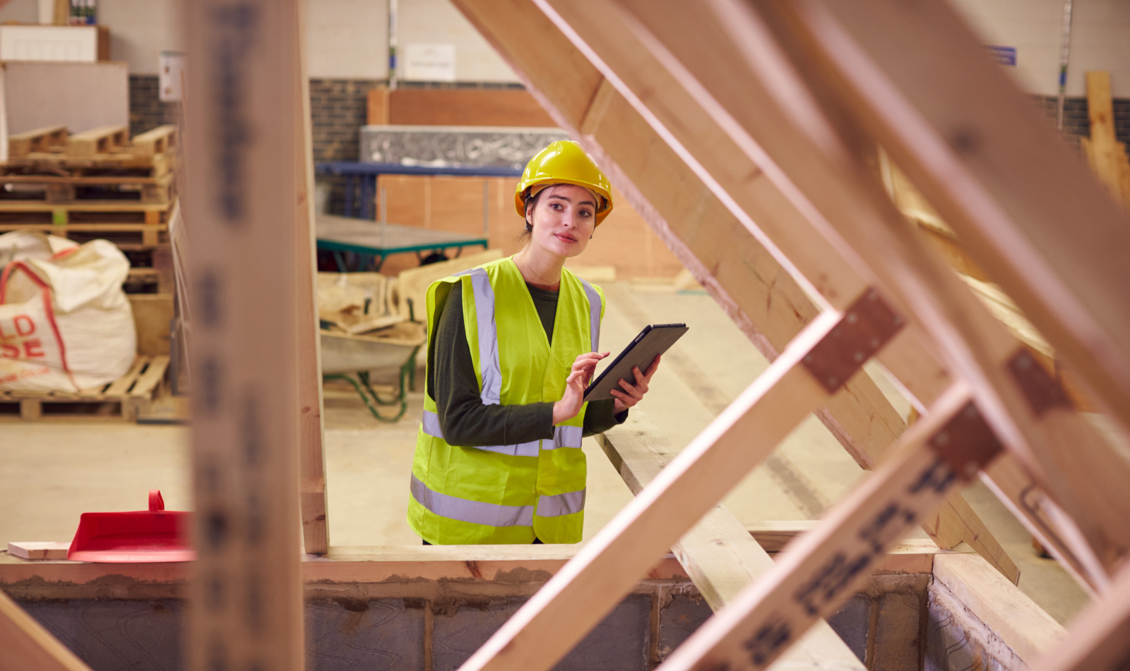 Female safety inspector working on a checklist within wooden construction site: Frame Homes UK and NestForms Offline Surveys