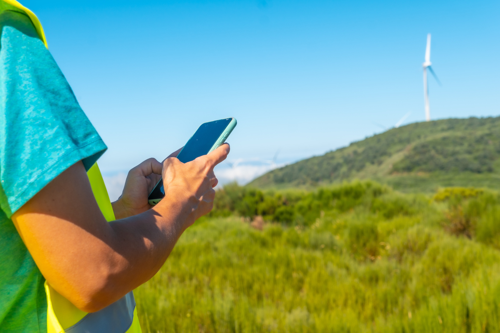 Land Surveyor with smartphone surveying land for wind turbine installation: NestForms Final Inspection Checklists
