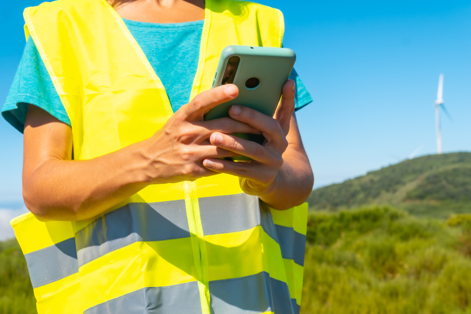 Concept image of female land surveyor with smart device, wind turbine in the background: The NestForms GPS Land survey app