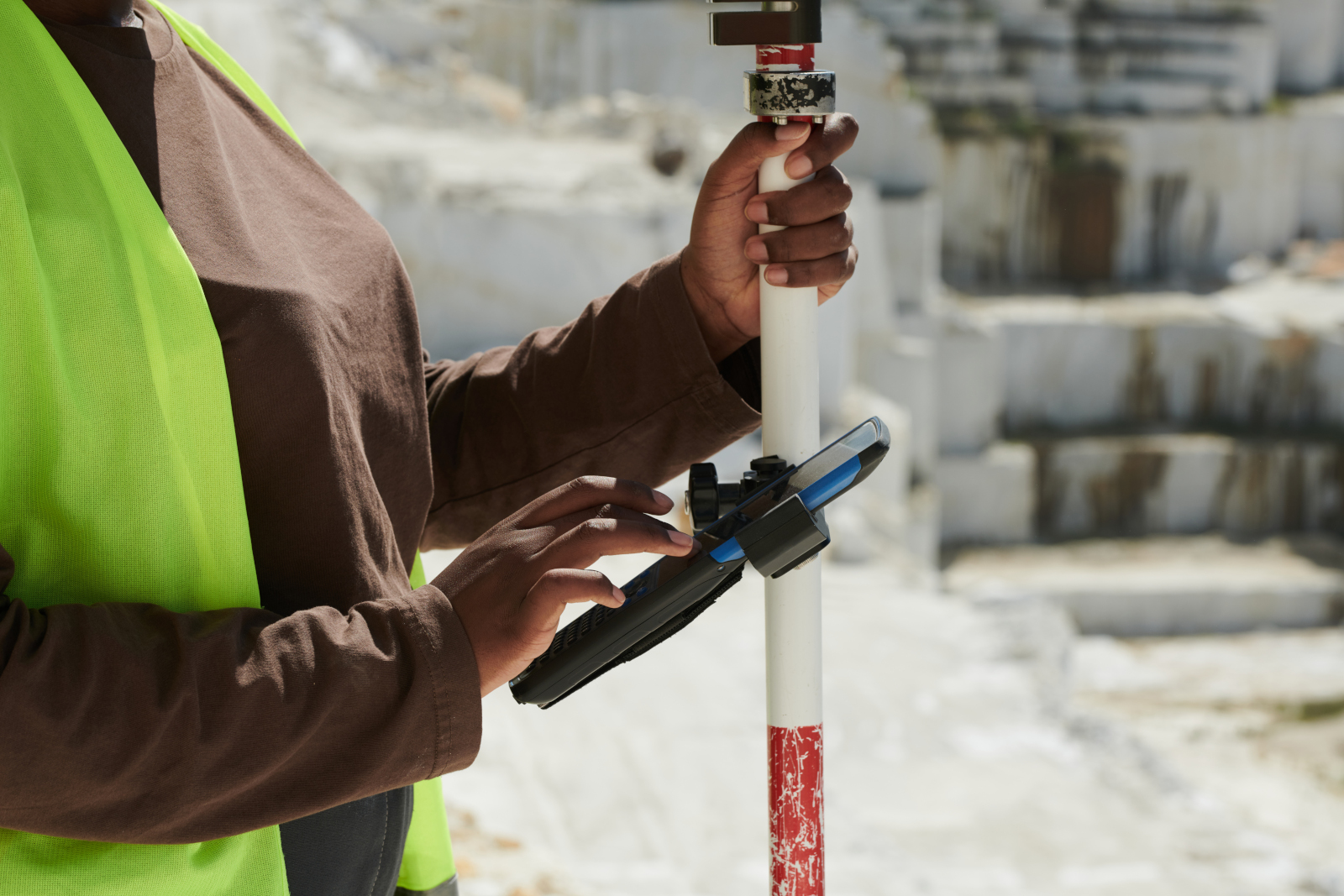 Female construction surveyor with surveying gear and smart device attached to a pole: The NestForms Surveyor App