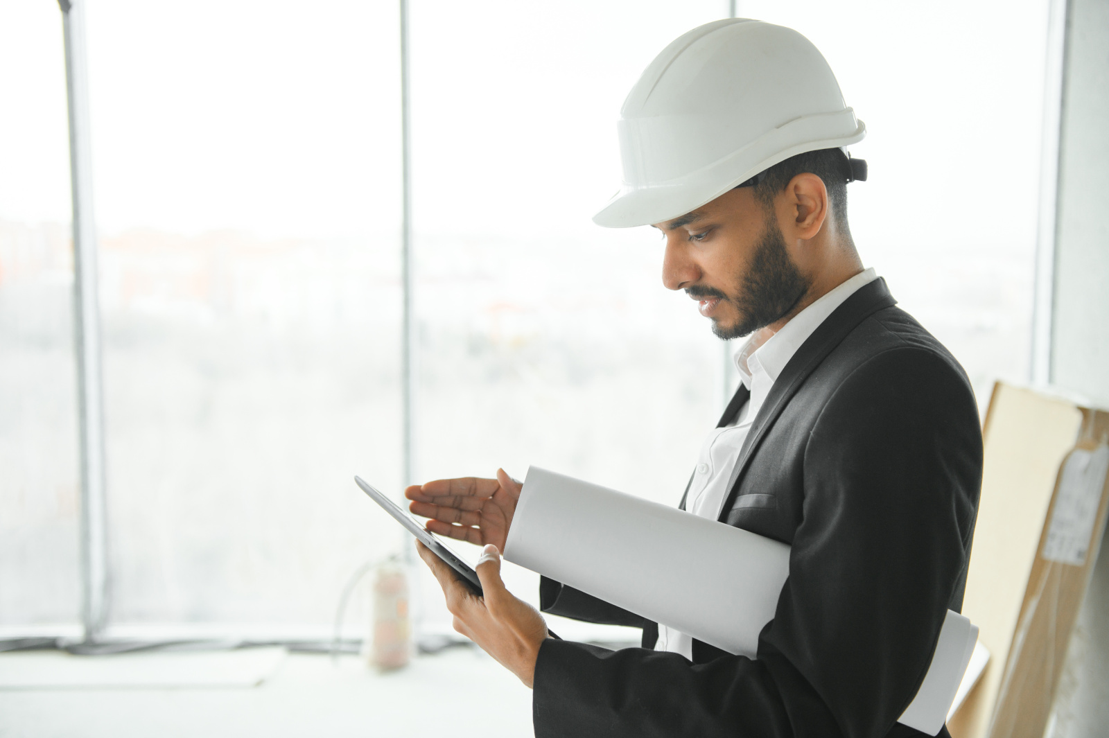 Construction site manager in safety helmet with smart device working on a project completion report created on NestForms
