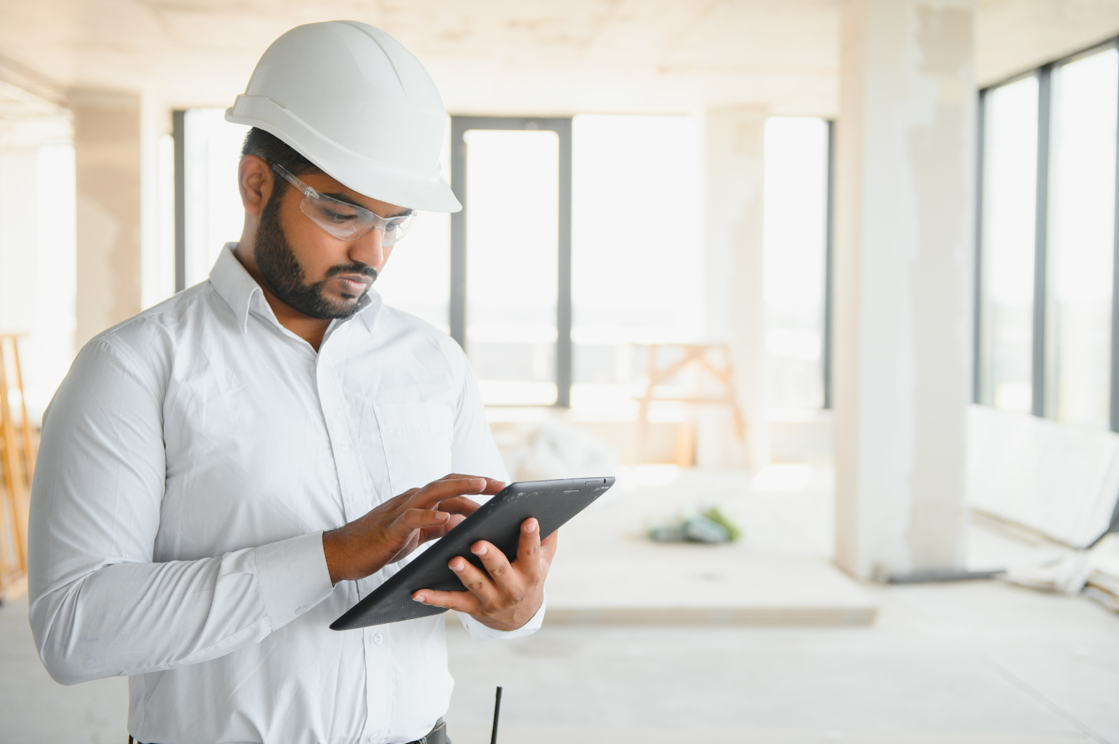 Construction worker with tablet filling completion forms during the final project phase: The NestForms form builder app