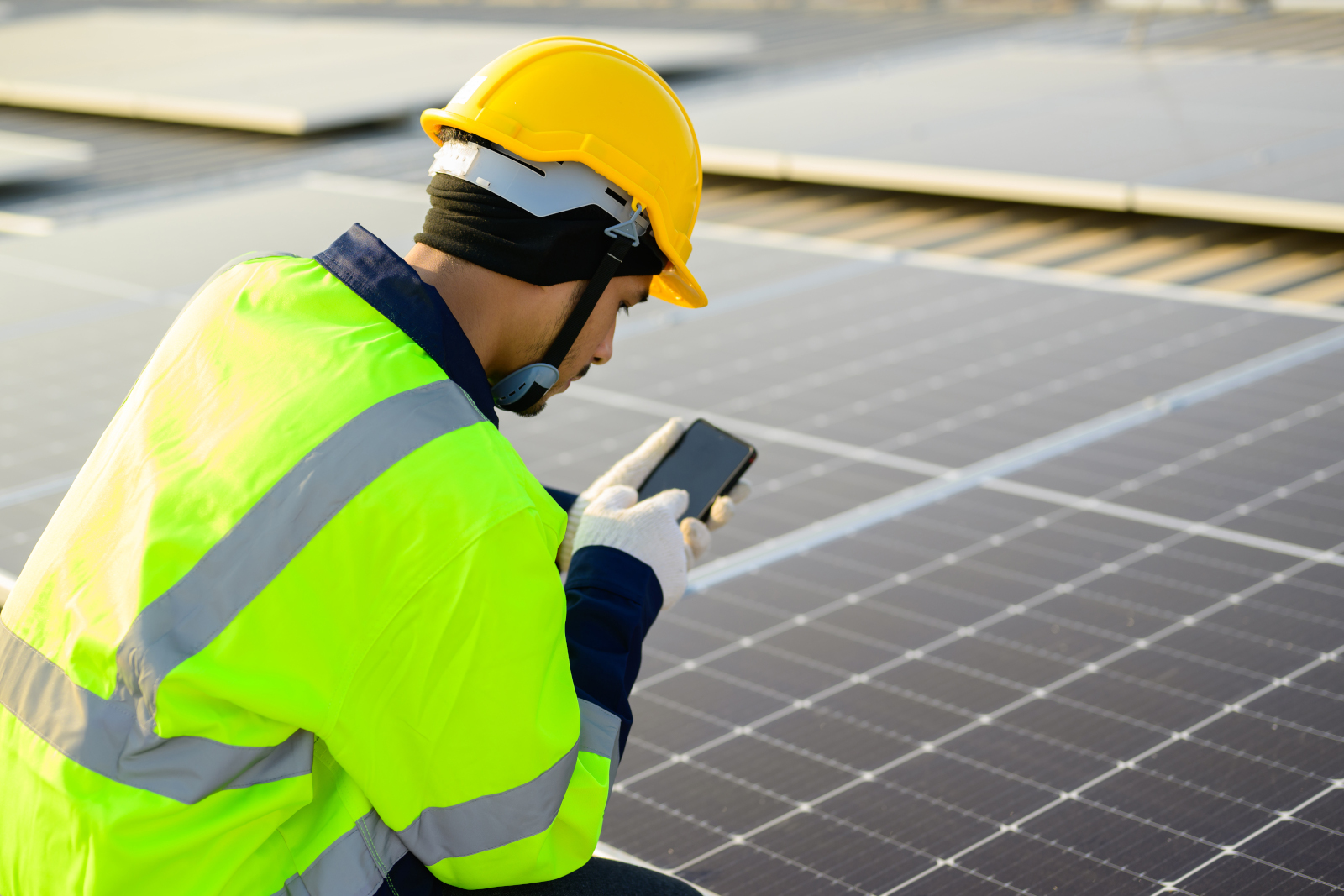 Solar panel engineer in safety gear with smart device inspecting new panelling: the NestForms Offline Survey App