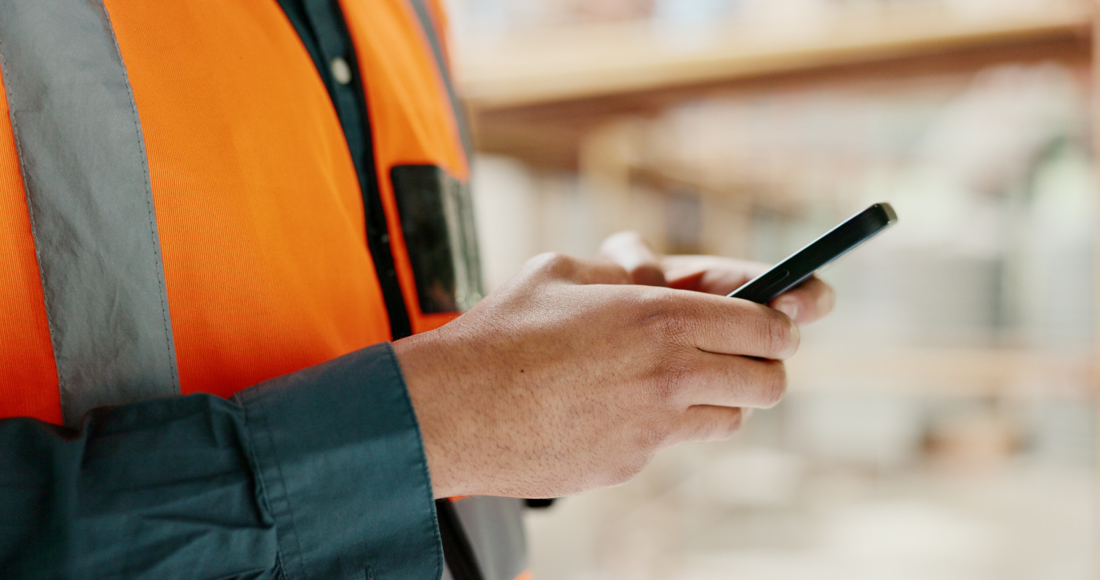 Concept image of construction worker in safety clothing holding smartphone and using the NestForms mobile form app