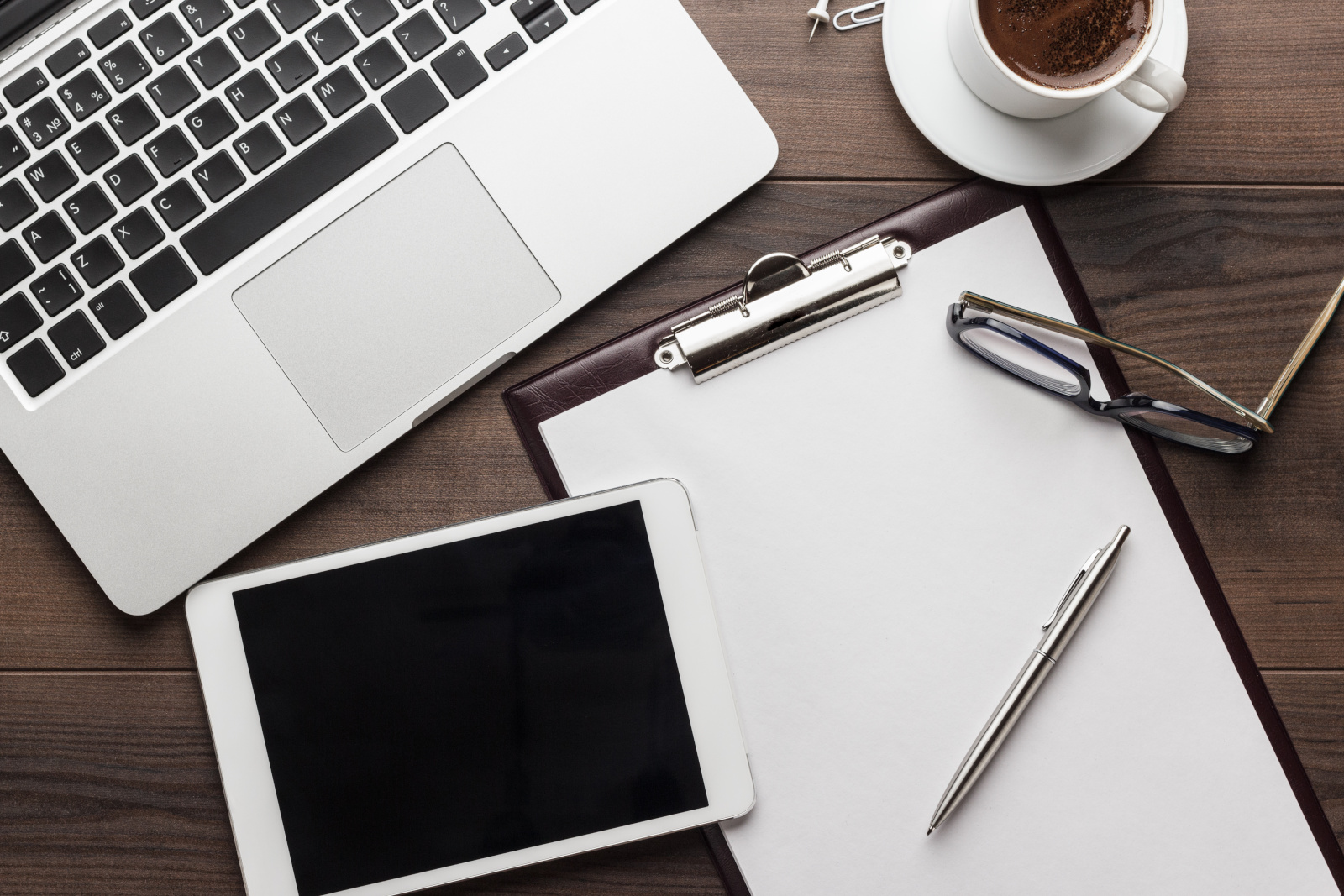 A tablet, a laptop, and a clipboard on a desk suggesting working with digital and paper: The NestForms offline survey app