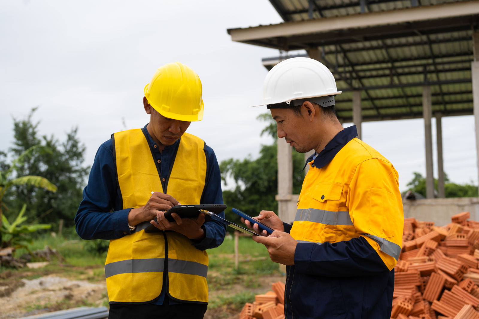 Two asian construction managers discussing completion forms and site handover forms: NestForms offline surveys