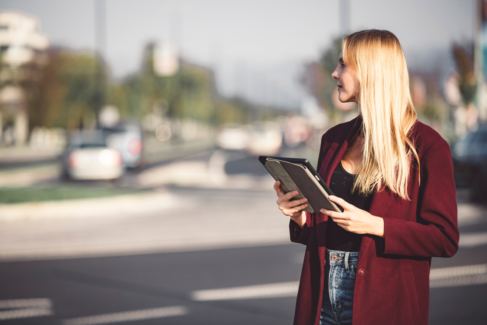 A young business woman using a digital tablet on the street, a glass skyscraper in background: NestForms Offline Survey App