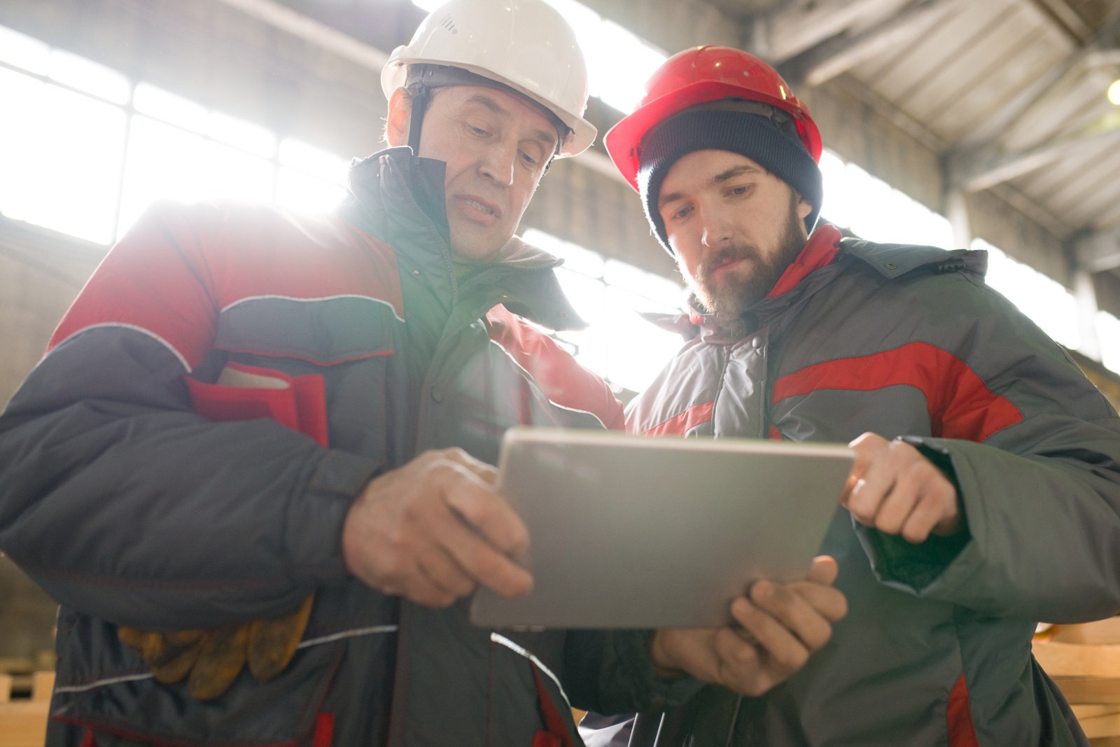 Two construction engineers in factory setting with tablet: Project Tracking forms with NestForms mobile data collection