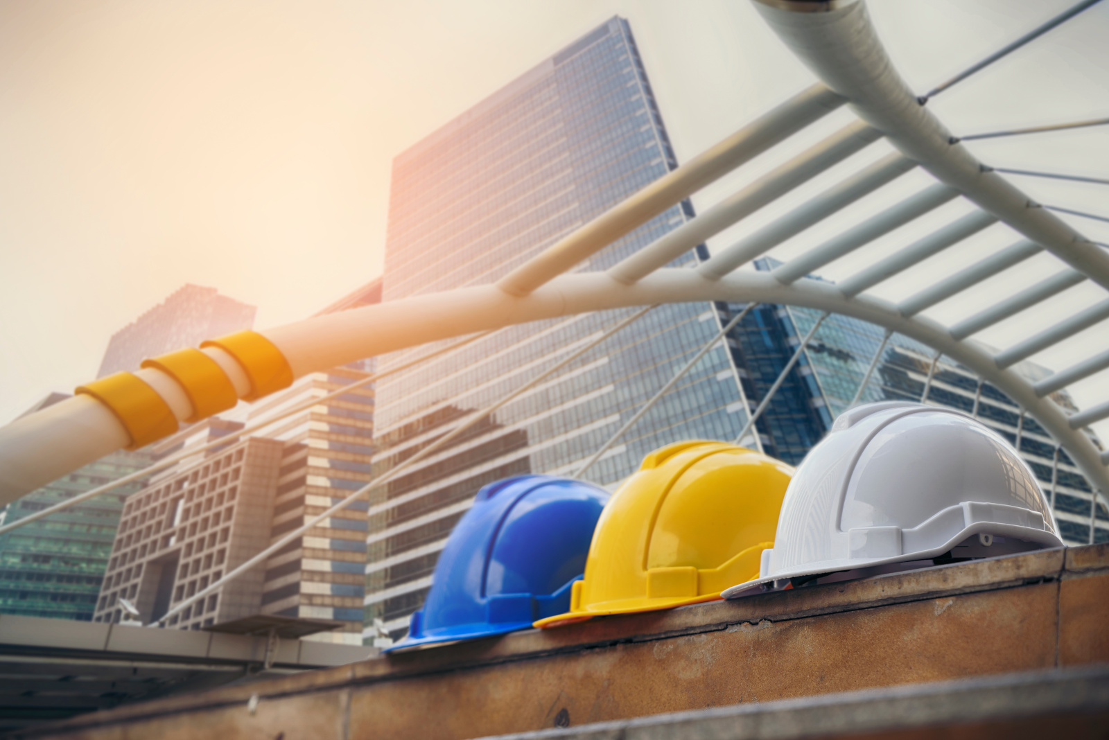 Blue, yellow and white protective helmets in front of high rise building as Health and Safety concept