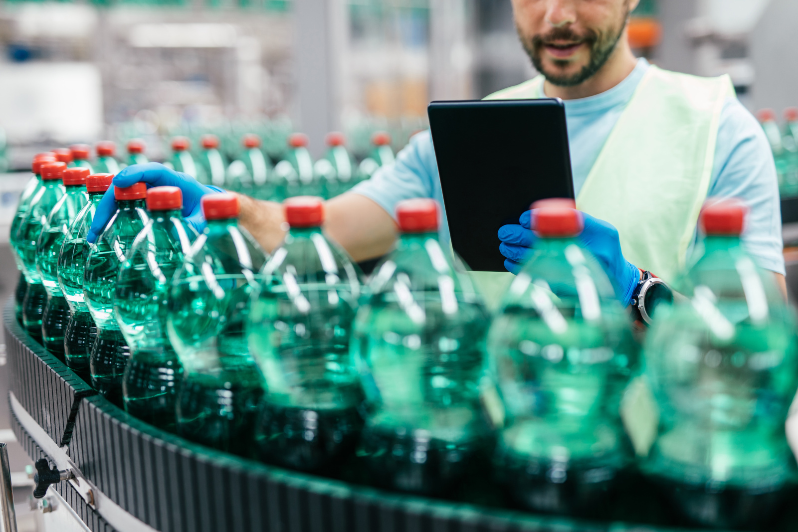 Quality Control auditor inspecting bottling on production line, with smart device and using the NestForms offline survey app